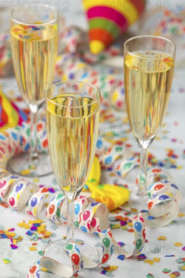 Three champagne glasses with colorful hats and confetti on a table, carnival