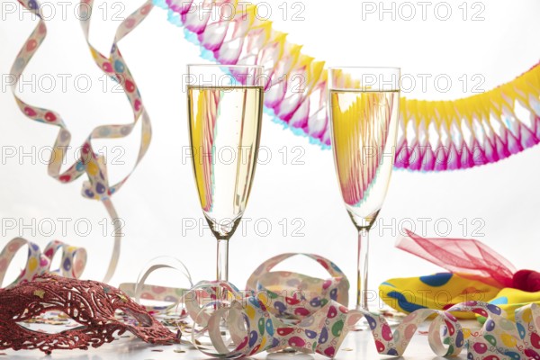 Two champagne glasses surrounded by decorative colorful streamers, carnival