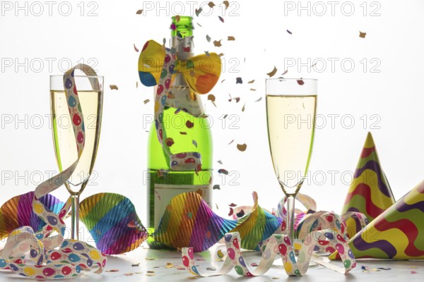 Champagne glasses and bottle surrounded by streamers and confetti, carnival
