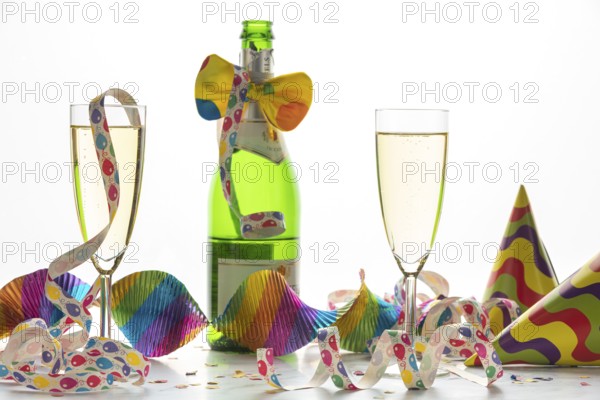 Two filled champagne glasses in front of a decorated bottle, Mardi Gras
