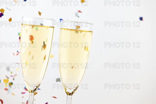 Two champagne glasses with colorful confetti in the background