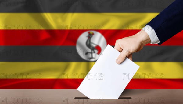 Uganda presidential vote 2026. Hand placing a ballot in ballot box with the Ugandan flag in the background