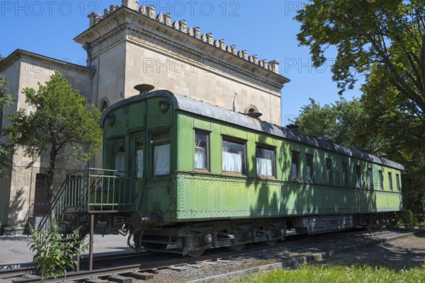 Old green railroad car in front of historic building and trees, Stalin's personal railroad wagon, Gori, Inner Kartli region, Georgia