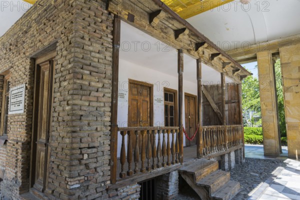 Rustic wooden veranda on a brick building with wooden windows, Josef Stalin's birthplace, Gori, Inner-Kartli region, Georgia