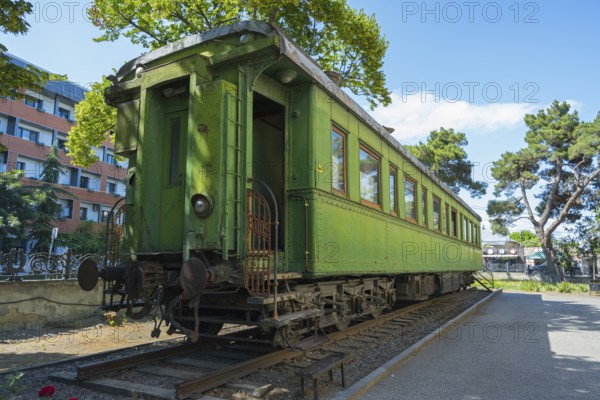 Green historic train car on rails between trees in an urban environment, Stalin's personal railroad car, Gori, Inner Kartli region, Georgia