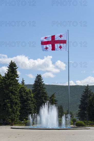 Large Georgian flag flying over a fountain in front of a hilly landscape, Stalin Park, Gori, Inner Kartli region, Georgia
