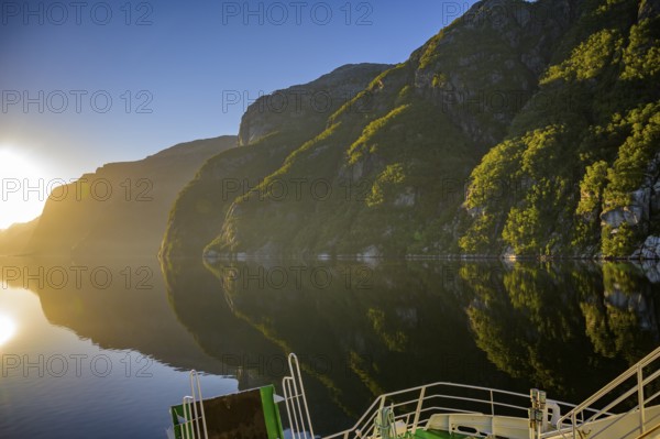 Tranquil fjord shore of Lyseford, illuminated by soft evening light with reflecting waters and dark mountains, view from the Columbus ferry, Lysefjord, Rogaland, Norway