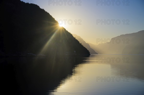 Sun shines over a mountain in the Lysefjordfjord bathed in calm, soft light, view from the Columbus ferry, Lysefjord, Rogaland, Norway