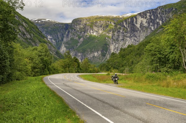 Åndalsnes, Møre og Romsdal province, Norway, Winding road with a motorcycle surrounded by green mountain scenery