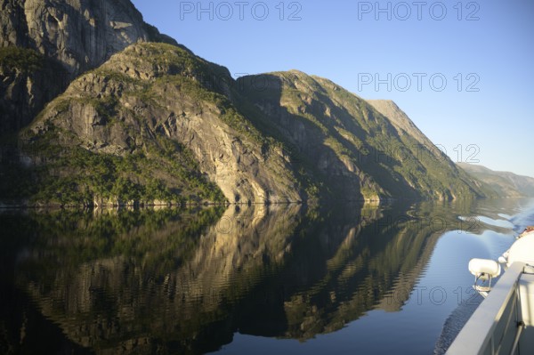 A boat sails along an orderly and peaceful Lysefjord surrounded by massive rock walls, Lysefjord, Rogaland, Norway
