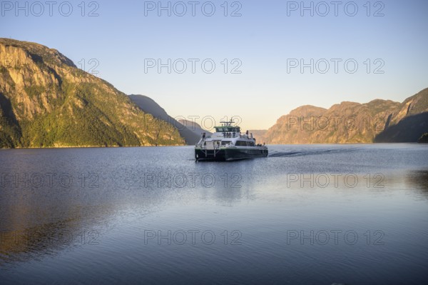 Columbus shipping company ferry moves through the Lysefjord with mountains in the background in the light of the morning sun, Lysefjord, Rogaland, Norway