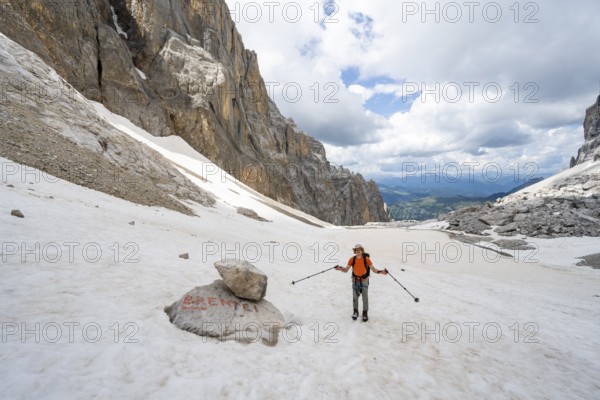 Mountaineers on a snowfield, guide to Rifugio Brentei on a rock, remains of the Vedretta dei Camosci glacier, Brenta Mountains, Brenta-Adamello Natural Park, Trentino, Italy