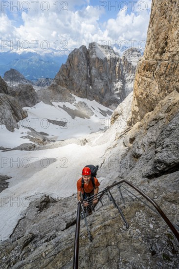 Mountaineer climbs a ladder, Via Ferrata dell'Ideale via ferrata, spectacular mountain landscape with steep rock faces, remains of the Vedretta dei Camosci glacier in the back, Brenta Mountains, Parco Naturale Brenta-Adamello, Trentino, Italy