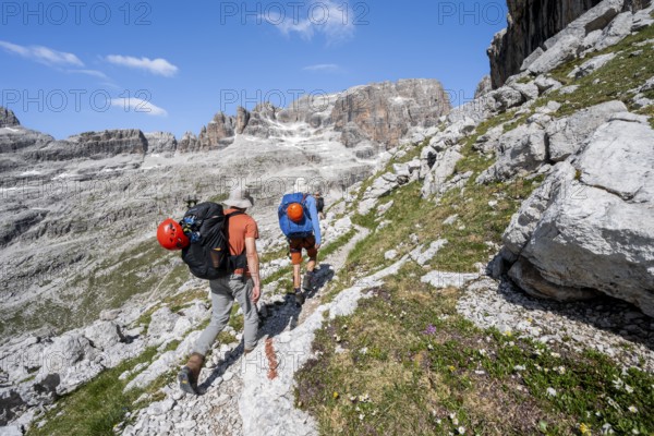 Two mountaineers on a hiking trail to Sella della Tosa, mountainous landscape in the Brenta Mountains, Brenta-Adamello Natural Park, Trentino, Italy