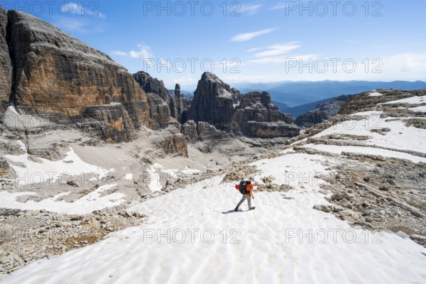 Mountaineers in a snowfield on the Sella della Tosa, mountain landscape with steep cliffs, Brenta Mountains, Brenta-Adamello Natural Park, Trentino, Italy