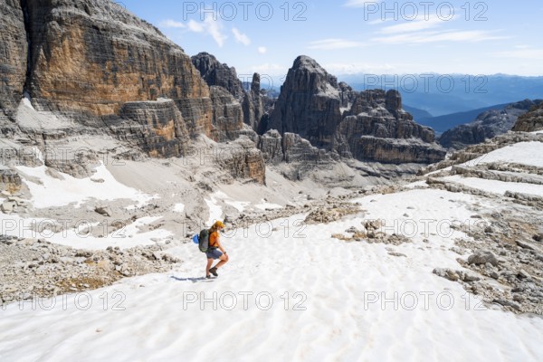 Female mountaineer in a snowfield on the Sella della Tosa, mountain landscape with steep cliffs, Brenta Mountains, Brenta-Adamello Natural Park, Trentino, Italy