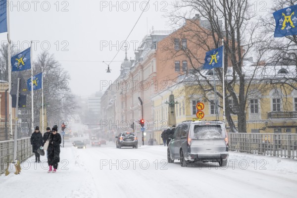 Pedestrians and cars on the snow-covered Auransilta bridge that crosses the Aurajoki River, wintery Turku or Swedish Åbo, Varsinais-Suomi, Finland