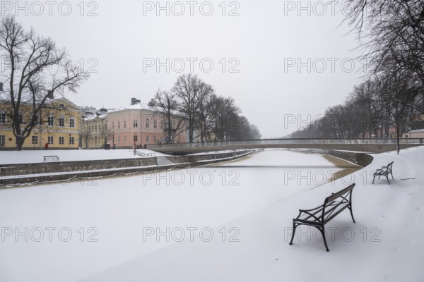 Benches, historic buildings on the frozen Aurajoki River, wintery Turku or Swedish Åbo, Varsinais-Suomi, Finland