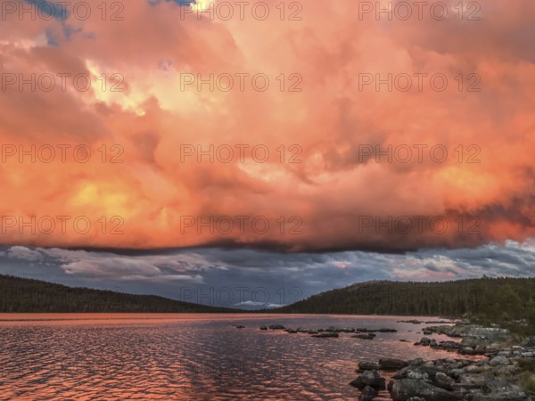 Impressive sky with intense colors reflected in the calm lake, Gutulia National Park, Drevsjö, Engerdal, Innlandet, Norway