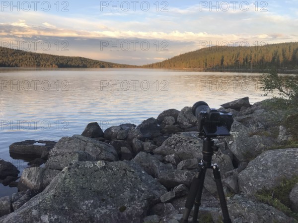 Drevsjø, Innlandet, Norway, camera on a tripod on a lake shore of Gutulsjön made of stones with sunset atmosphere, Gutulia National Park, Engerdal, Innlandet, Norway