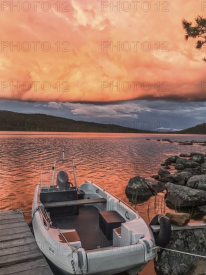 Boat moored on a jetty under a dramatic, colorful sky, Gutulia National Park, Engerdal, Innlandet, Norway