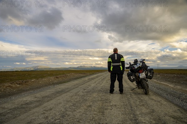 Falkvålen, Bruksvallarna, Jämtland, Sweden, BMW G 650 GS Sertao Enduro motorcyclist standing next to a BMW G 650 GS Sertao Enduro motorcycle on an empty country road with a wide view of the sky