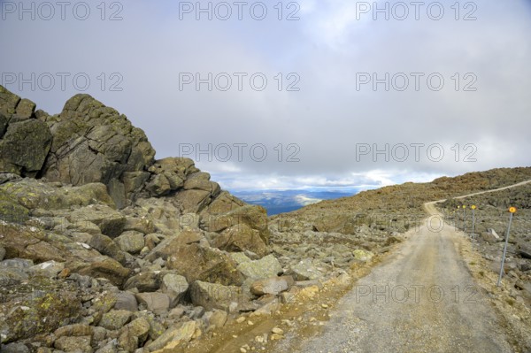 Alvdal, Innlandet, Norway, Rocky road leads through a barren mountain landscape under cloudy sky, Sweden's highest passable road