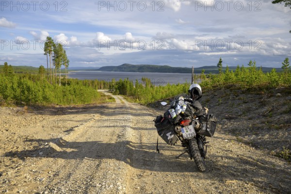 Lövdalen, Jämtland County, Sweden, BMW G 650 GS Sertao enduro motorcycle on a dirt road with views over vast countryside and lake