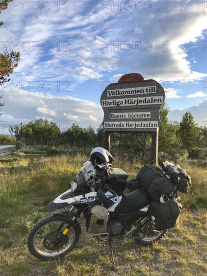 Funäsdalen, Jämtlands län, Sweden, BMW G 650 GS Sertao Enduro motorcycle is standing at a welcome sign Wonderful Härjedalen in a rural area with blue sky