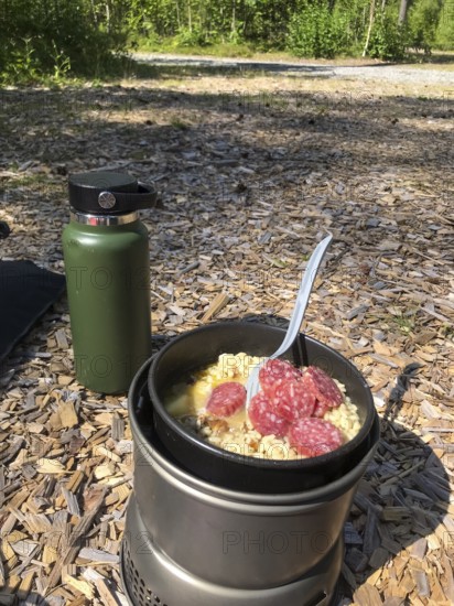 Hällefors, Örebro län, Sweden, outdoor meal on a camping stove with salami and noodles in the forest