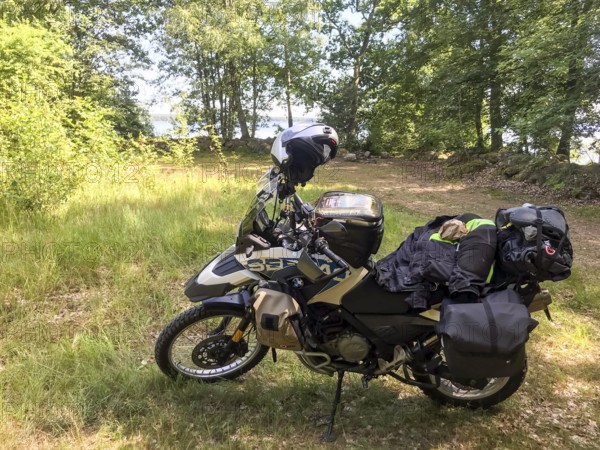 Kalvsvik, Kronobergs län, Sweden, BMW G 650 GS Sertao enduro motorcycle in the forest with packed luggage and helmet, surrounded by nature, Asnen National Park