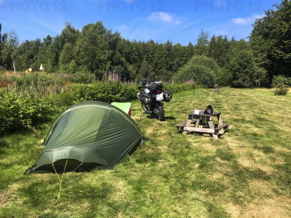 Växjö, Kronobergs län, Sweden, campsite with tent and BMW G 650 GS Sertao enduro motorcycle in a meadow under a blue sky, Asnen National Park