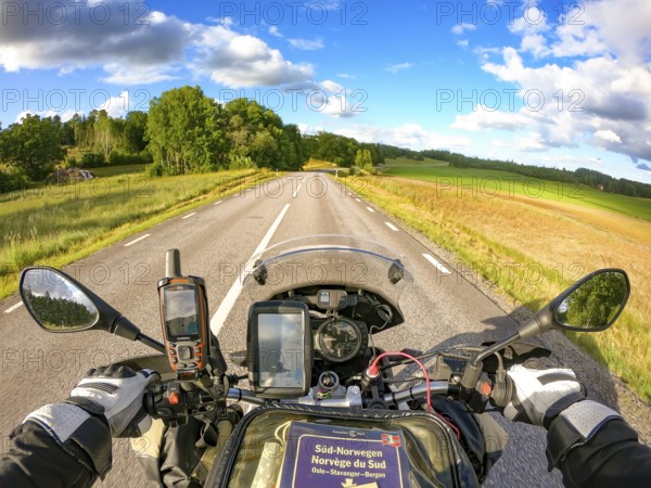 Stjärnhov, Södermanlands län, Sweden, BMW G 650 GS Sertao Enduro motorcyclist on an open country road with a clear view of the landscape under a blue sky, looking from the cockpit over the handlebars onto the country road