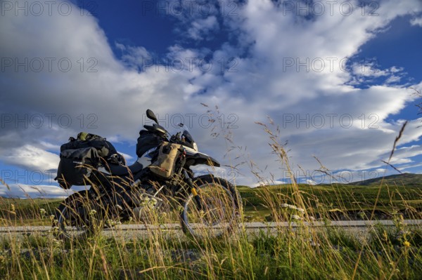 Dalholen, Innlandet, Norway, BMW G 650 GS Sertao enduro motorcycle on a road through an extensive meadow landscape under clouds