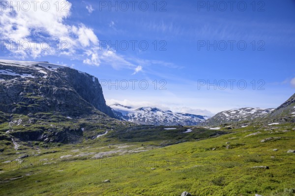 Geiranger, Møre og Romsdal province, Norway, green fields against snow-covered mountains under clear skies