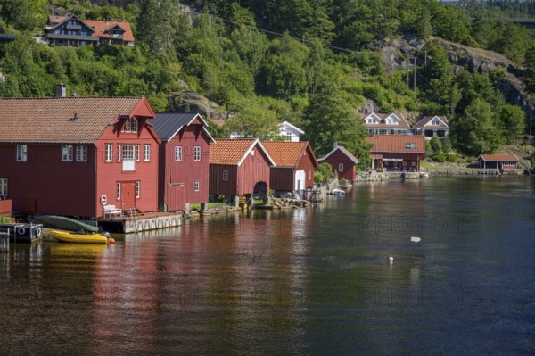 Feda, Agder, Norway, Red wooden houses boathouses along a forest surrounded by lush nature