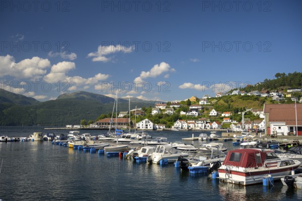 Sand, Rogaland municipality, Norway, boats in the harbor in front of a city with mountains and blue summer sky