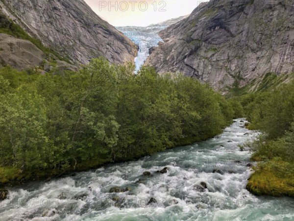 Briksdalsbre, Vestland, Norway, wild water flow through thick forests, with a glacier with Brikdalsbreen in the background