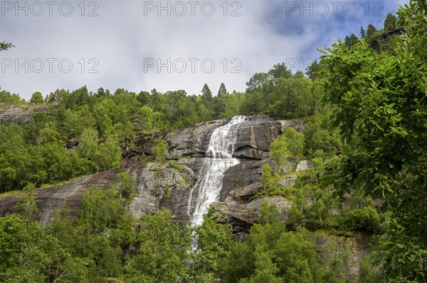 Åndalsnes, Møre og Romsdal Province, Norway, High Waterfall flows over steep rocks surrounded by lush greenery and trees