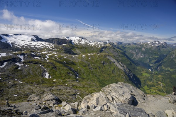 Geiranger, Møre og Romsdal province, Norway, view over snow-capped mountains and a green valley with the Geirtanger Fjord under blue sky, highest fjord view in Europe from the Geiranger Skywalk