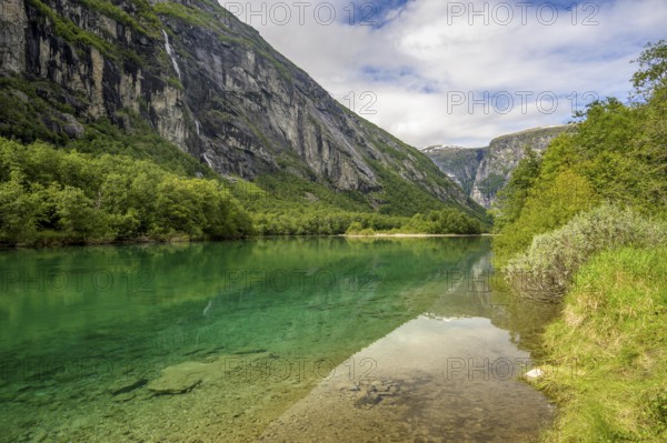 Åndalsnes, Møre og Romsdal province, Norway, Clear river surrounded by green landscape flanked by high mountains and blue skies