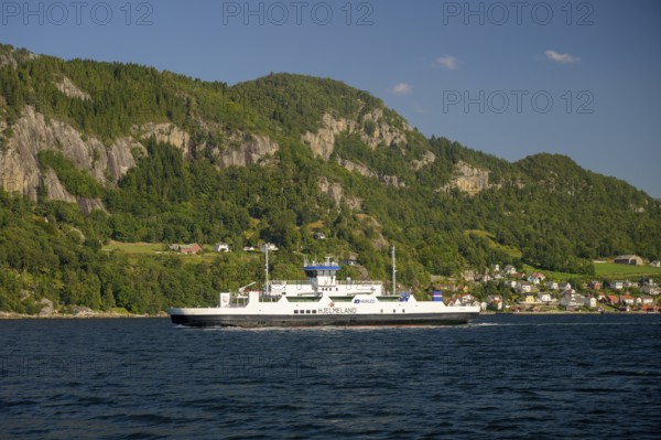 Hjelmeland, Rogaland Municipality, Norway, ferry on a fjord in front of a wooded landscape with mountains