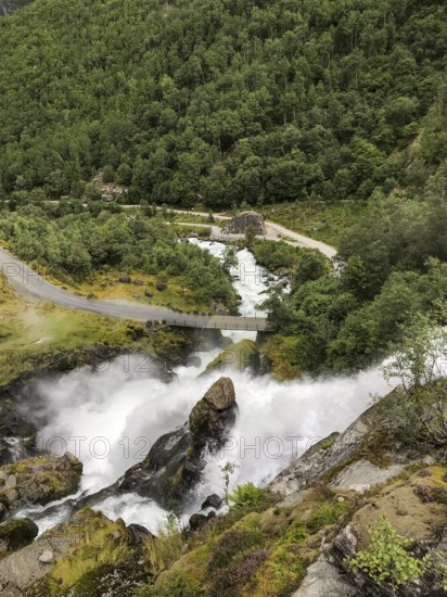 Briksdalsbre, Vestland, Norway, waterfall originating from the Brikdalsbreen glacier flows thunderously over rocks, surrounded by lush vegetation