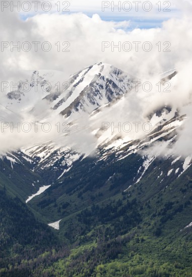 Fog sweeps around mountain peaks with remnants of snow, view from Slaughter Ridge Trail, Cooper Landing, Kenai Peninsula, Alaska, USA