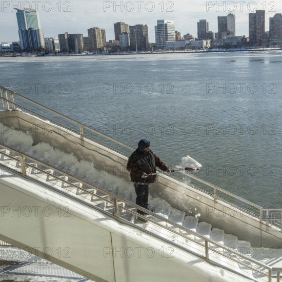 Detroit, Michigan USA - 15 January 2026 - A worker shovels snow from steps leading to Huntington Place convention center where the Detroit Auto Show is being held