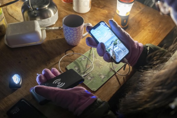 Symbolic picture blackout, extensive, prolonged power failure, in private surroundings, without electricity, heating, water, mobile phone is charged with a power bank