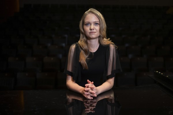 Young woman, pianist, in evening dress, with folded hands supported on Steinway & Sons grand piano, Stuttgart, Baden-Württemberg, Germany