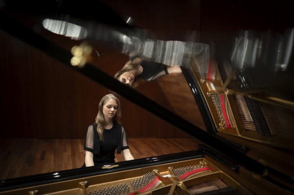 Young woman, pianist, in evening dress playing on an unfolded Steinway & Sons grand piano, Stuttgart, Baden-Württemberg, Germany