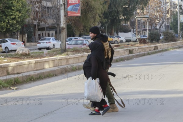 In Aleppo, Syria on January 10, 2026, Syrian Army soldiers assist and secure an elderly woman following fierce battles with the SDF. The deployment comes after Kurdish forces withdrew from the Sheikh Maqsoud and Ashrafieh neighborhoods towards eastern Syria, ending days of heavy military operations in the area, Aleppo, Sheikh Maqsood, Syria