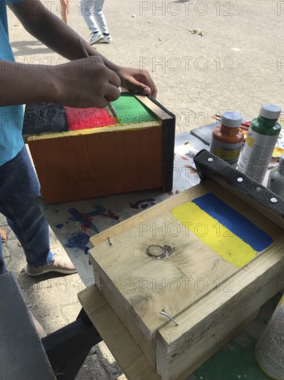 Lower Saxony, Germany, painted bird house in blue and yellow with flowers. Ukrainian students' creative craft project with spring-like design